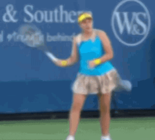a woman is holding a tennis racquet in front of a wall that says w & s