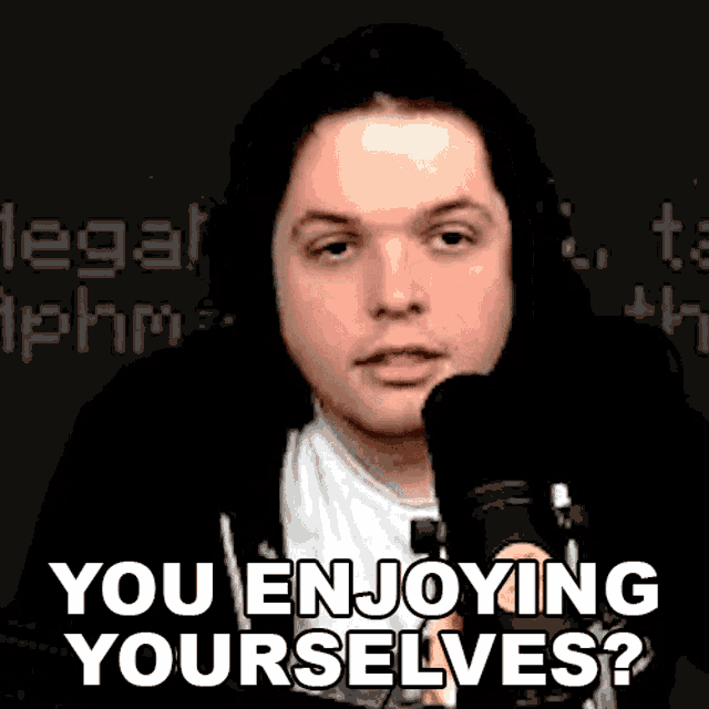 a man in headphones is sitting in front of a microphone and saying `` you enjoying yourself ? ''