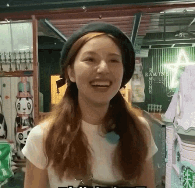 a woman wearing a black hat and a white t-shirt is smiling