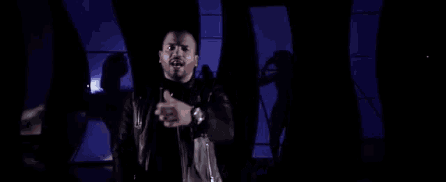 a man in a leather jacket is standing in front of a microphone .