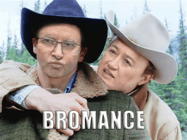 a man in a cowboy hat is holding another man in a blanket with the word bromance written on it