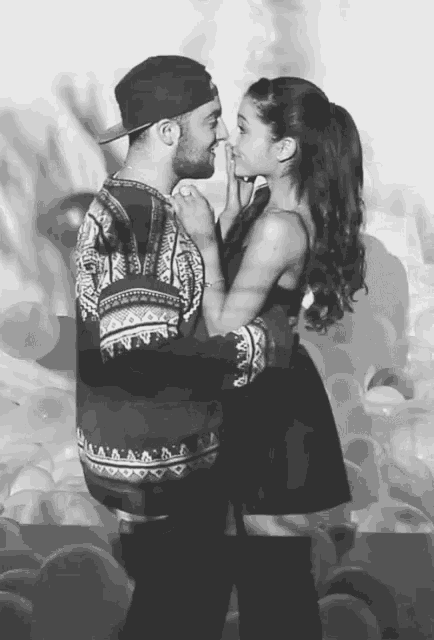 a black and white photo of a man and woman looking into each others eyes