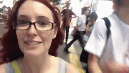 a woman wearing glasses is smiling while walking down a street