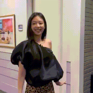 a woman in a black off the shoulder top and leopard print skirt is standing in front of a door .