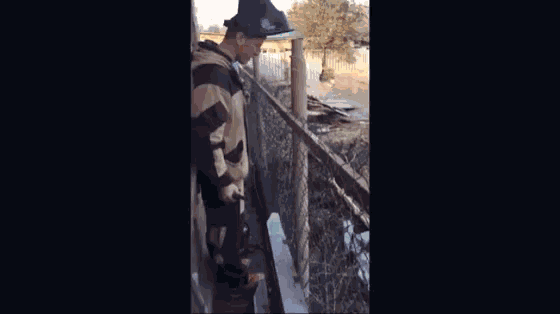 a man in a hard hat and overalls is standing on a balcony .