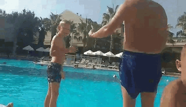 a man and a boy are standing in a swimming pool .