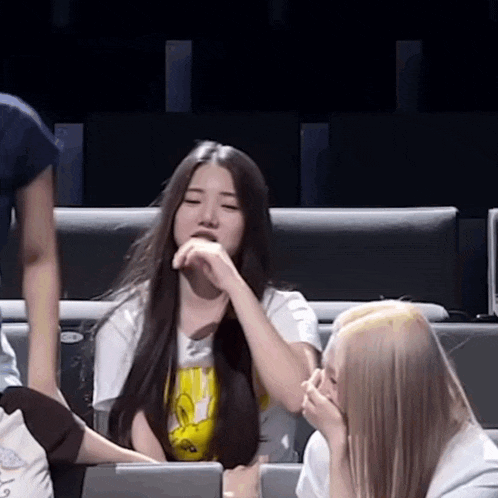 a woman with long hair is sitting on a couch with her hand on her face .