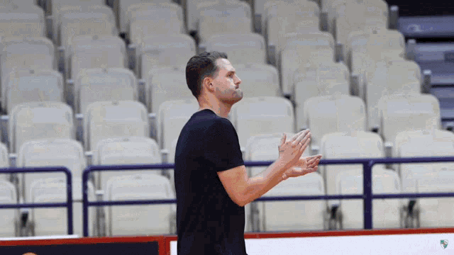 a man in a black shirt is standing in front of a row of empty seats