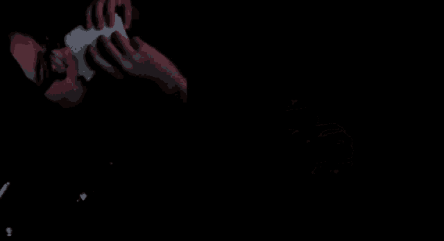 a person is holding a piece of paper in their hand in a dark room