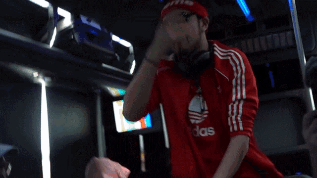 a man wearing a red adidas shirt stands in a crowd