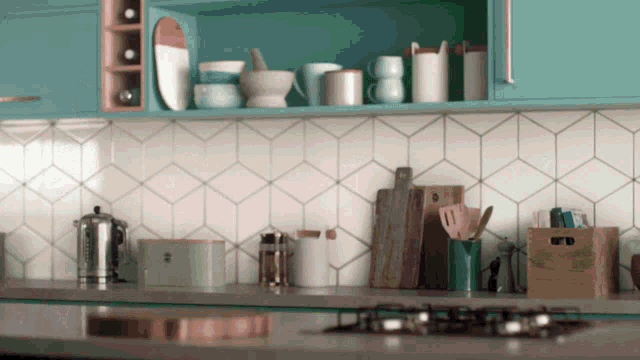 a kitchen with blue cabinets and white tiles has utensils on the counter and a cutting board