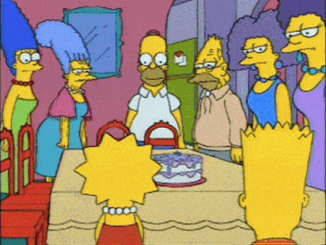 a group of simpsons characters gather around a table with a cake on it