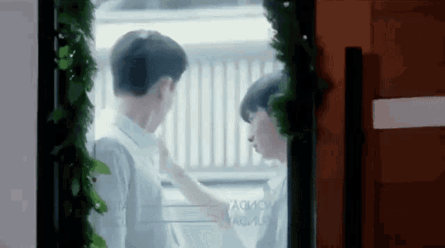 a couple of young men are standing next to each other in front of a window .