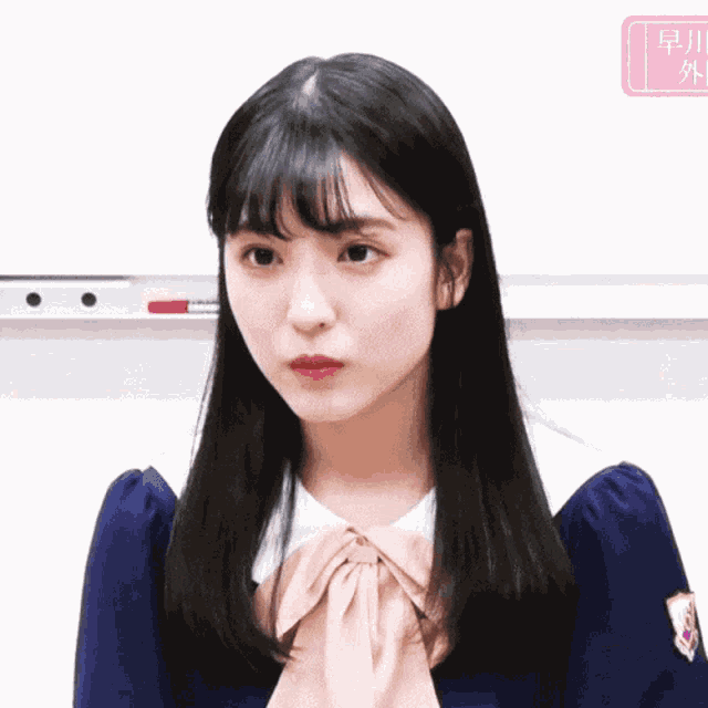 a girl in a blue dress with a white collar and a bow looks at the camera
