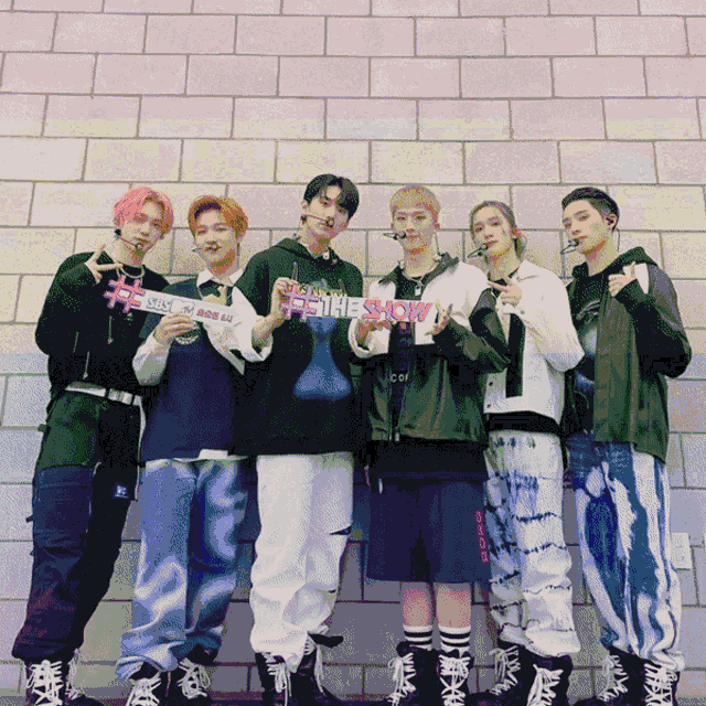 a group of people standing in front of a brick wall holding a sign that says ' miss you ' on it