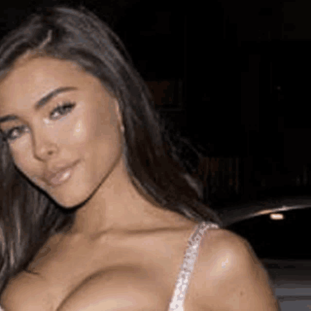 a woman in a bra is standing in front of a car .