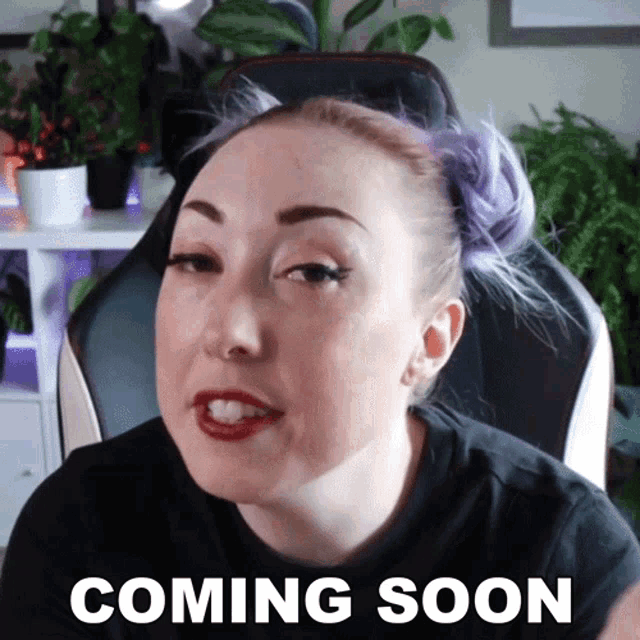 a woman with purple hair is wearing a black shirt that says " coming soon " on the front