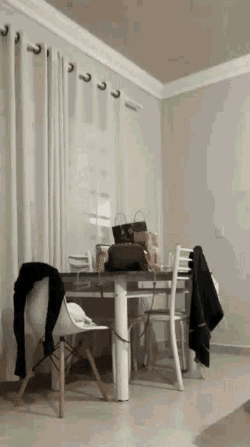 a dining room table and chairs in a living room with a purse on the table .
