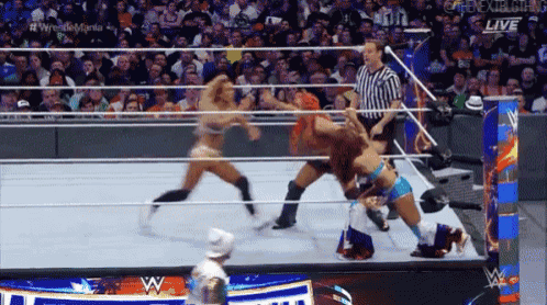 two women are wrestling in a wrestling ring with a referee and a sign that says live