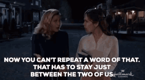 two women are standing next to each other on a street and one of them is talking to the other .
