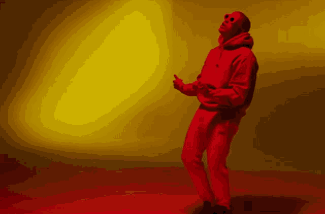 a man in a red hoodie and red sweatpants is standing in front of a yellow background