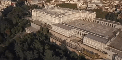 an aerial view of a large building surrounded by trees in a city