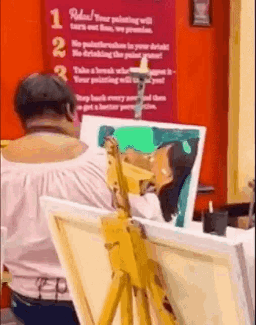 a woman is painting on a canvas on an easel .