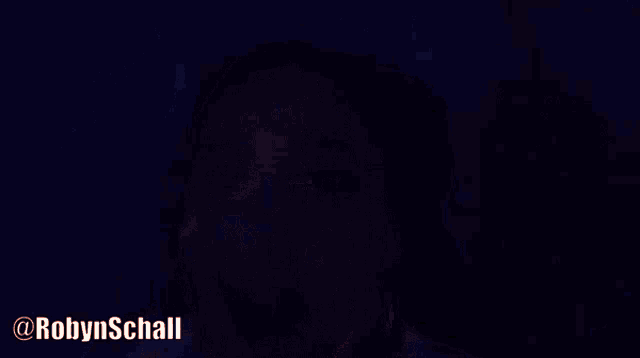a woman in a dark room with the name robyn schall above her