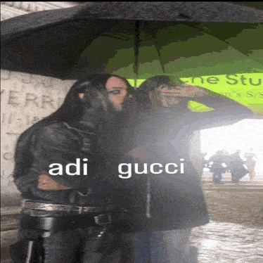 a couple standing under an umbrella with adi gucci written on it