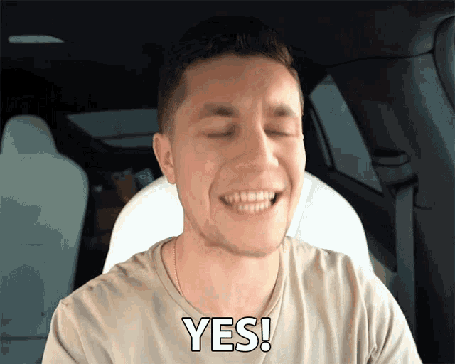 a man in a car with his eyes closed and the word yes on his chest