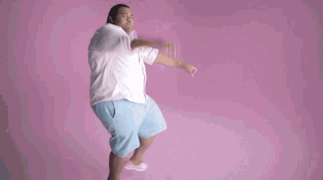 a man in a white shirt and blue shorts is jumping in the air .