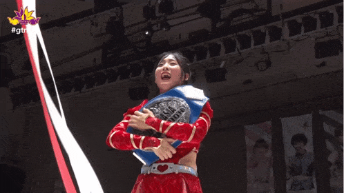 a woman in a red and gold outfit is holding a asian championship belt
