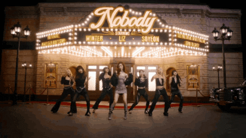 a group of women dancing in front of a nobody sign