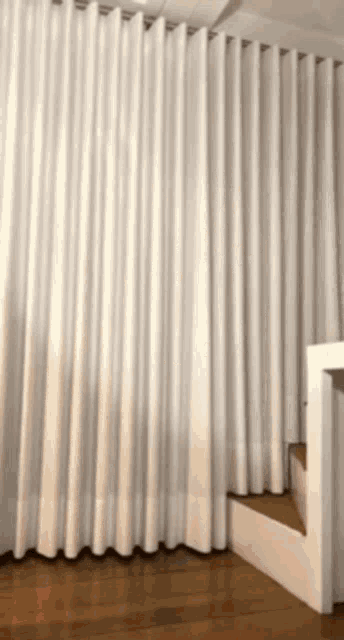 a white curtain is hanging on a wall next to a set of stairs