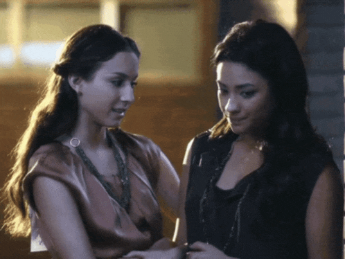a couple of women standing next to each other looking at something