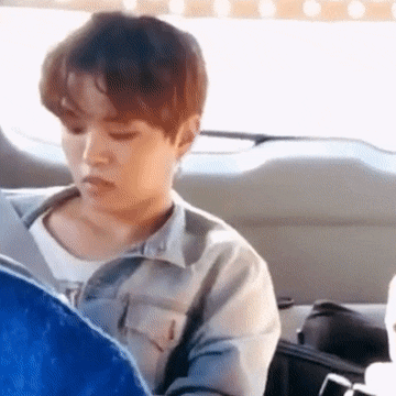 a young man is sitting in the back seat of a car looking at something .