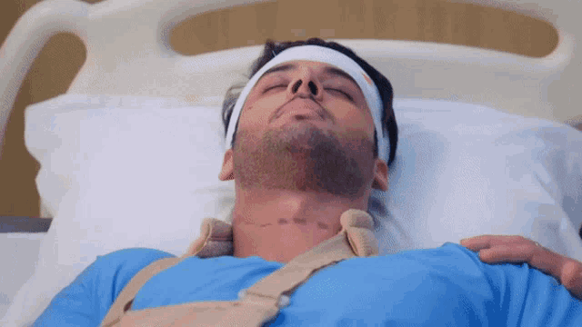 a man laying in a hospital bed with a bandage on his head