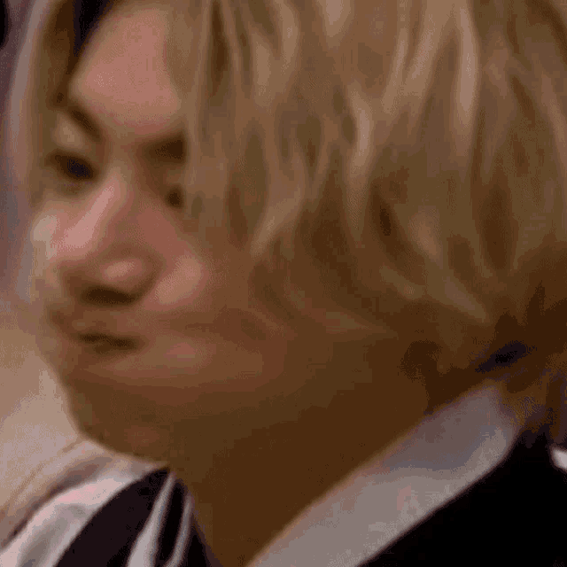 a close up of a man 's face with long blonde hair .