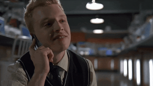 a man in a vest is talking on a cellphone