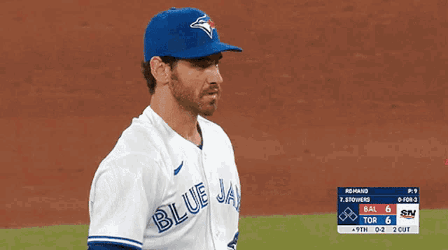 a man wearing a blue jays jersey stands on a field