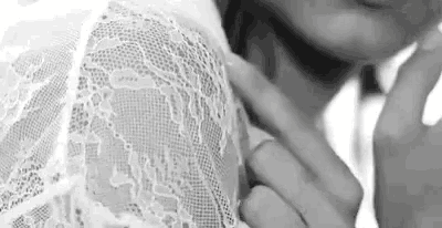 a black and white photo of a woman wearing a lace dress .