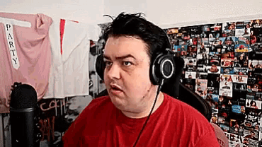 a man wearing headphones is sitting in front of a wall with a shirt that says party on it