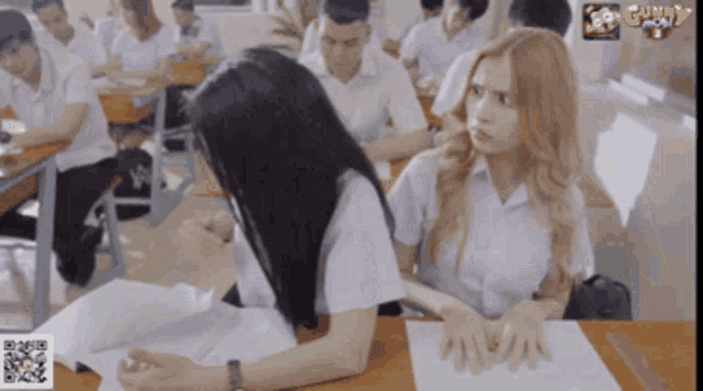 a girl sits at a desk in a classroom with a guntv logo on the bottom