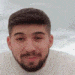 a man with a beard is wearing a white sweater and smiling .
