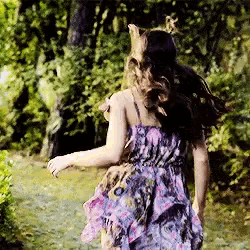 a girl in a floral dress is running through a forest