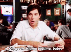 a man is sitting at a table with a plate of food and saying oh yeah hit me bigtime baby