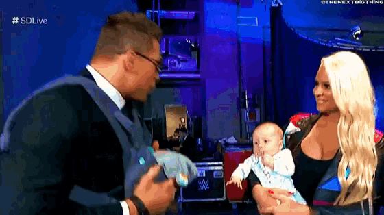 a man and a woman are holding a baby in front of a blue background .
