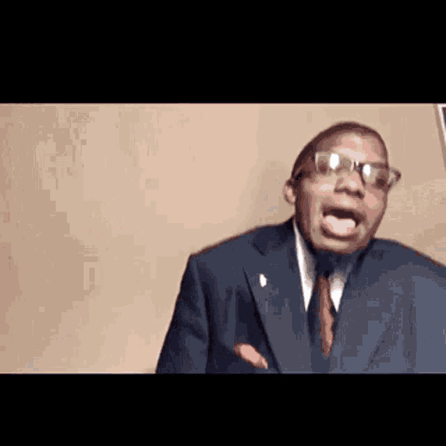 a man in a suit and tie is making a funny face with his tongue out .