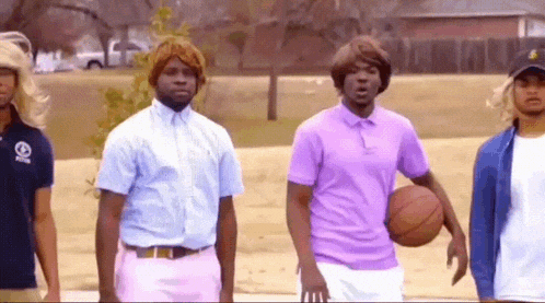 a man in a purple shirt is holding a basketball in front of two other men