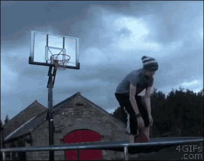 a man is jumping over a railing in front of a basketball hoop